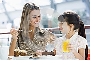 Mother and daughter eating cake in cafe