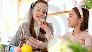 Mother, daughter eating delicious chocolate eggs