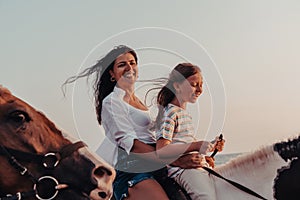 Mother and daughter enjoy riding horses together by the sea. Selective focus