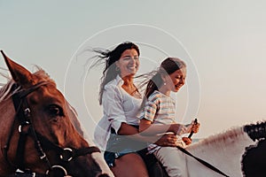 Mother and daughter enjoy riding horses together by the sea. Selective focus