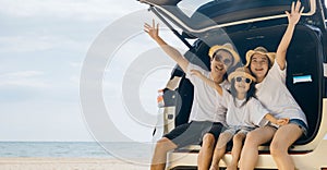 Mother and daughter enjoying road trip sitting on family back car raise hand up