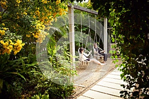 Mother and daughter enjoying the swing chair in the beautiful relaxing cozy garden