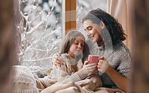 Mother and daughter enjoying winter nature in the window