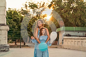 Mother daughter family sunset. Portrait of mother and daughter in blue dresses with flowing long hair against the