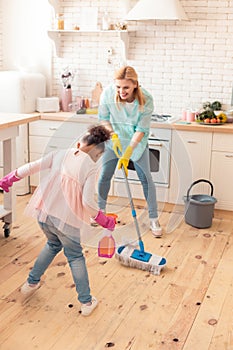 Mother and daughter feeling cheerful cleaning flat together