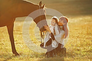 Mother and daughter in a field playing with a horse