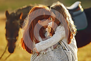 Mother and daughter in a field playing with a horse