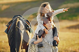 Mother and daughter in a field playing with a horse