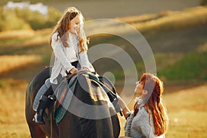 Mother and daughter in a field playing with a horse