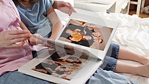 mother and daughter flip through a photobook with photos of a family photo shoot