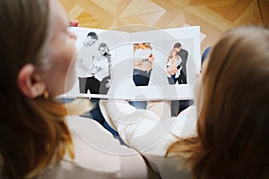 mother and daughter flips through a book with photos of dad and pregnant mom.