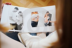 Mother and daughter flips through a book with photos of dad and pregnant mom. photo