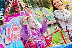 Mother and daughter at fun fair, chain swing ride