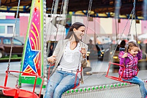 Mother and daughter at fun fair, chain swing ride