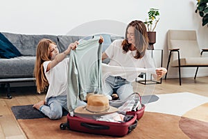 Mother and daughter going on trip pack suitcase