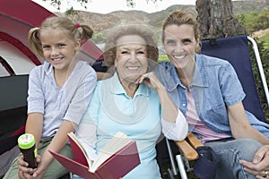Mother, Daughter And Granddaughter Reading Outside Tent
