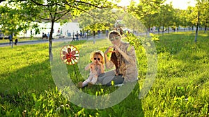 Mother and daughter happily spend time playing together on the grass at sunset.