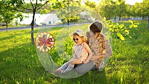 Mother and daughter happily spend time playing together on the grass at sunset.