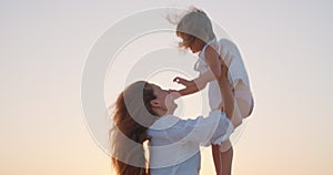 Mother and daughter. Happy family baby a kid dream concept mother throws his daughter in the coast ocean at sunset