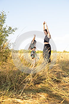 Mother and daughter have fun and dance in the summer field in nature. Mother& x27;s Day, happy motherhood and spending
