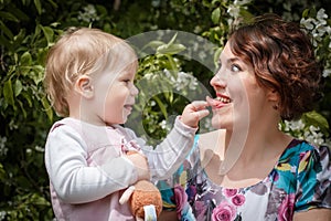 Mother and daughter have fun in the park and apple tree with white flowers