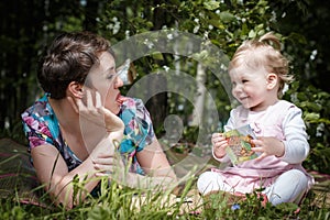 Mother and daughter have fun in the park and apple tree with white flowers