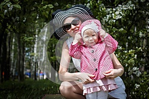 Mother and daughter have fun in the park and apple tree with white flowers