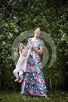 Mother and daughter have fun in the park and apple tree with white flowers