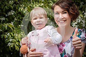 Mother and daughter have fun in the park and apple tree with white flowers