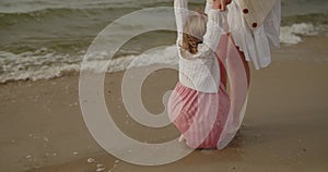 Mother and daughter have fun playing in the sea water on the beach together