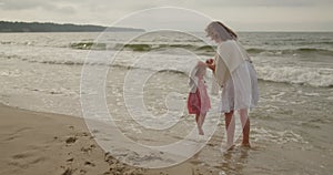 Mother and daughter have fun playing in the sea water on the beach together