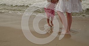 Mother and daughter have fun playing in the sea water on the beach together