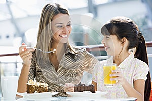 Mother and daughter having cake at cafe
