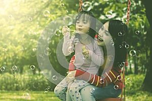 Mother and daughter having fun blowing soap bubbles at park