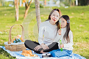 Mother and daughter having fun blowing soap bubbles during a picnic