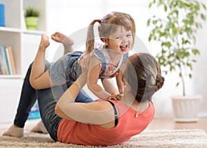 Mother and daughter having a fun on floor at home. Woman and child relaxing together.