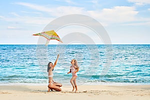 Mother and daughter having fun flying a kite on tropical beach