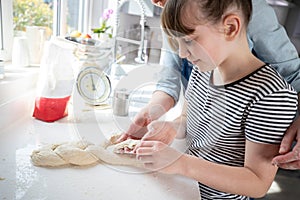 Mother And Daughter Having Fun In Kitchen At Plaiting Dough For Home Baked Bread Together