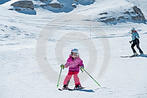 Mother and daughter having fun and learning skiing making first steps on a ski winter resort at mountain hill.