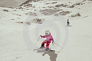 Mother and daughter having fun and learning skiing making first steps on a ski winter resort at mountain hill.