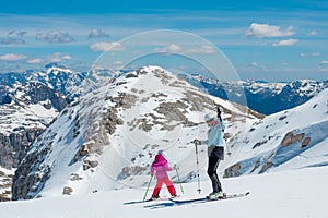 Mother and daughter having fun and learning skiing making first steps on a ski winter resort at mountain hill.