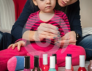 Mother and daughter having fun painting fingernails