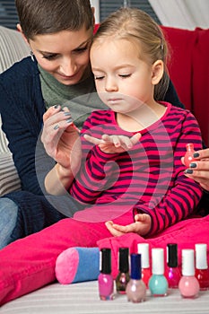 Mother and daughter having fun painting fingernails