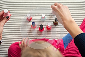 Mother and daughter having fun painting fingernails, view from above