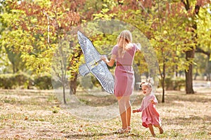 Mother and daughter having fun on a park background. Family flying a kite. Motherhood concept. Copy space.