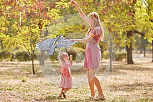 Mother and daughter having fun on a park background. Family flying a kite. Motherhood concept. Copy space.