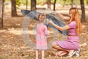 Mother and daughter having fun on a park background. Family flying a kite. Motherhood concept. Copy space.