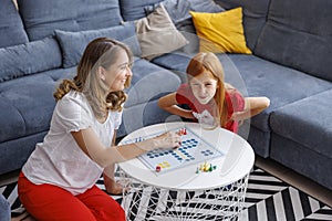 Mother and daughter having fun playing ludo board game