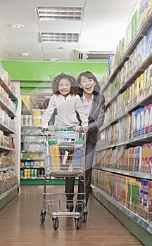 Mother and Daughter Having Fun in Supermarket, Pushing Cart