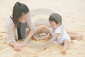 Mother and daughter are having a fun time playing in the beach sand together